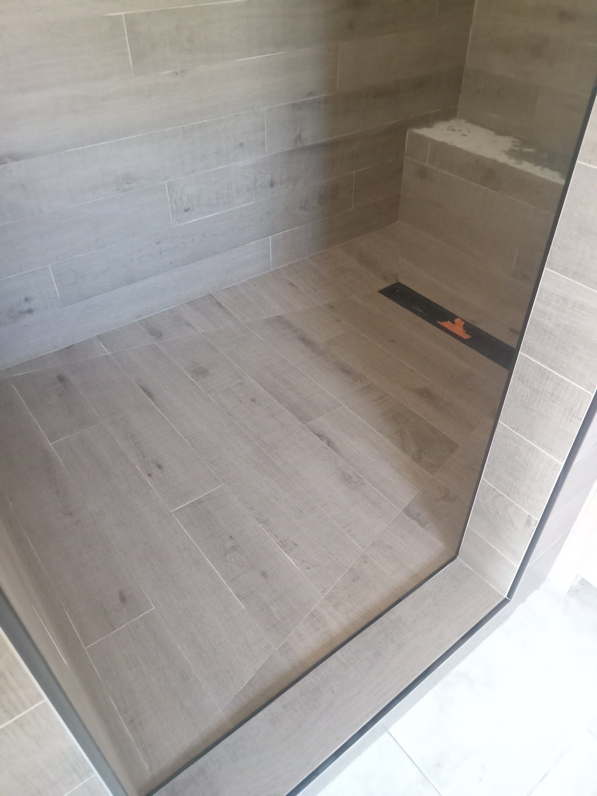 A bathroom with a walk in shower and a bench.