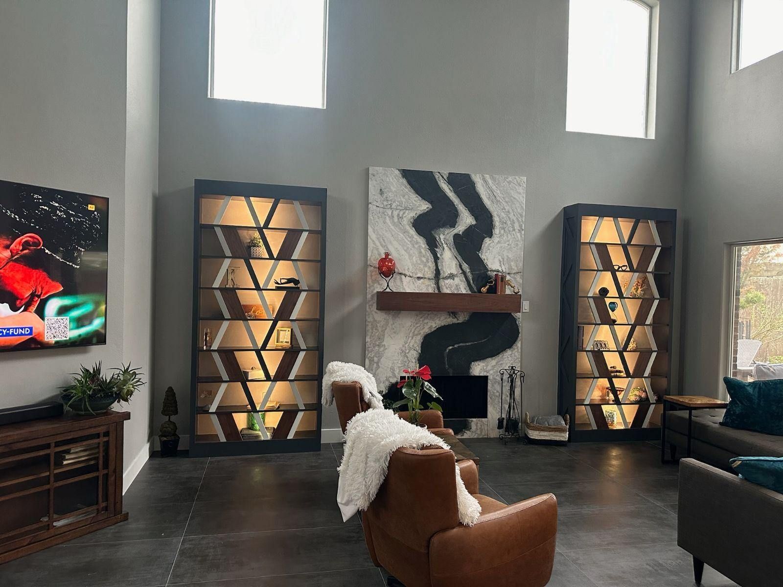 A living room with a fireplace , chairs , and a flat screen tv.