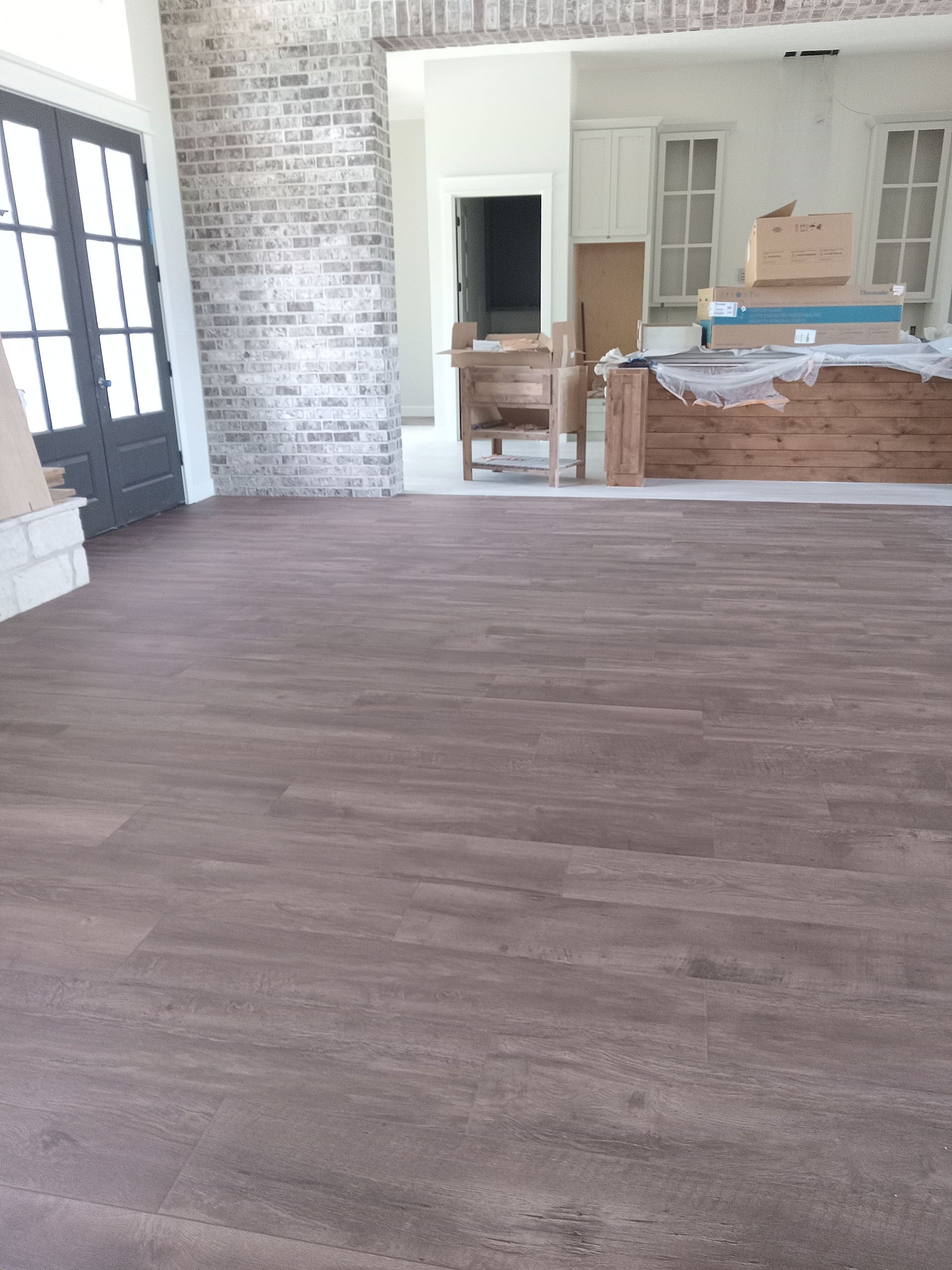 A living room with a wooden floor and a brick wall