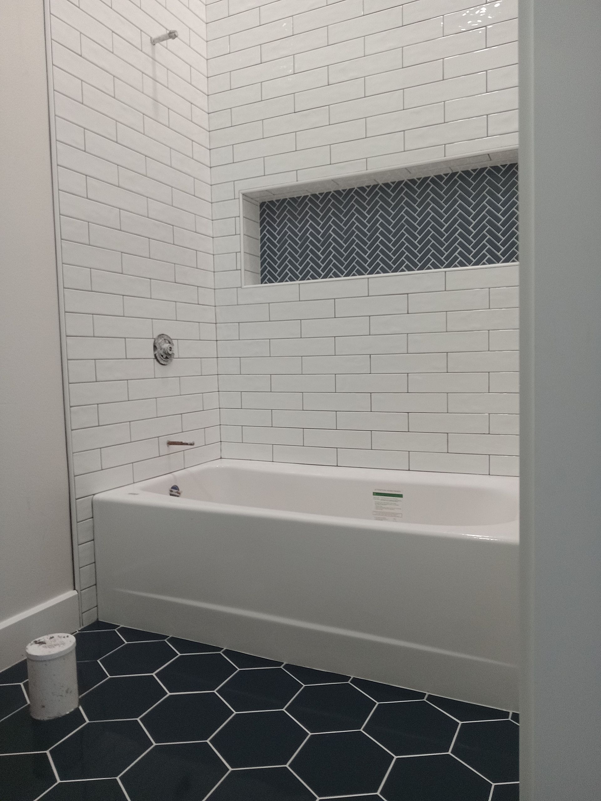 A bathroom with white tiles and a bathtub