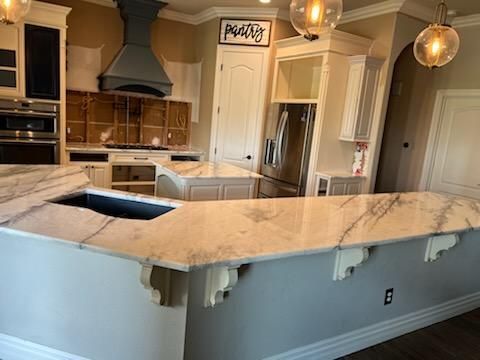 A kitchen with a large island and marble counter tops.