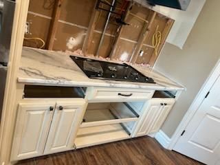 A kitchen with white cabinets and a stove top oven.