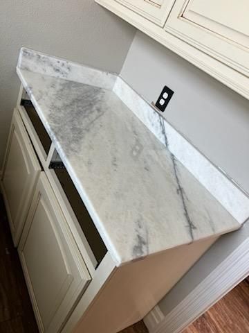 A white cabinet with a marble counter top in a kitchen.