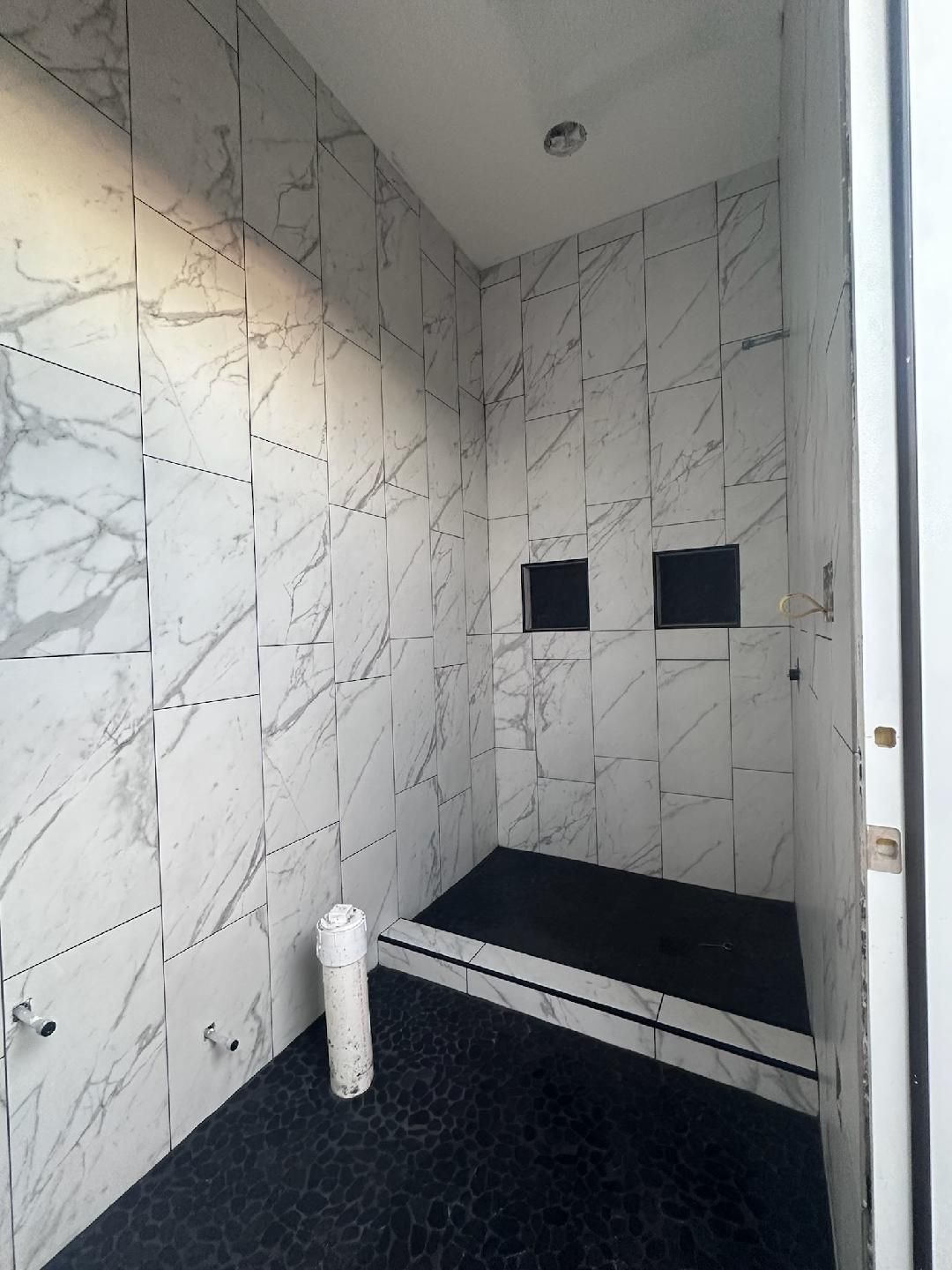 A bathroom with marble tiles and a black floor.