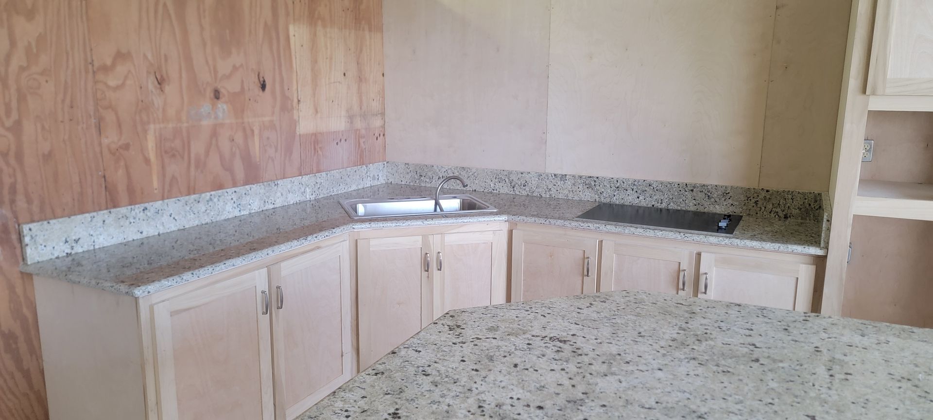 A kitchen with granite counter tops , cabinets and a sink.