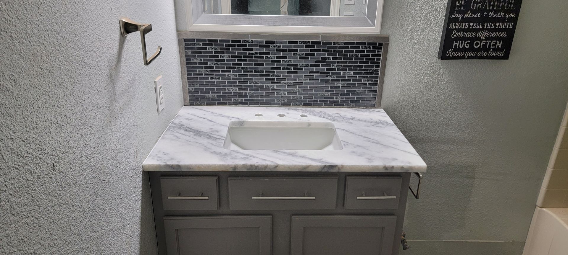 A bathroom with a sink , mirror and towel rack.
