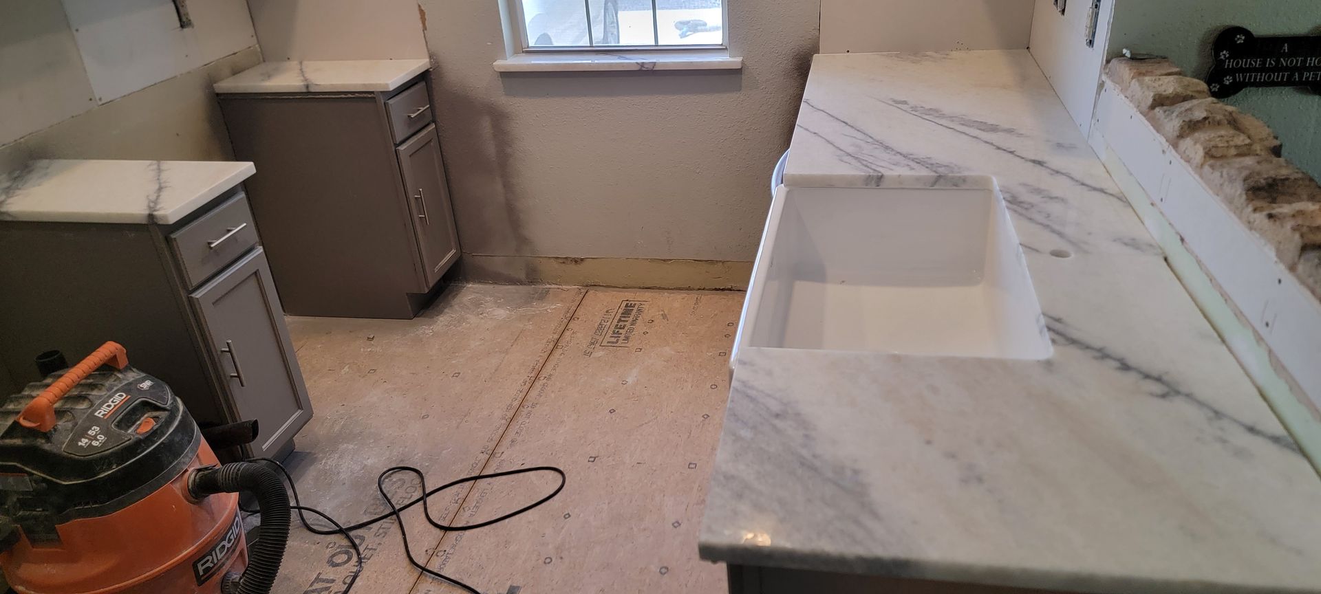 A vacuum cleaner is sitting on the floor in a kitchen next to a sink.