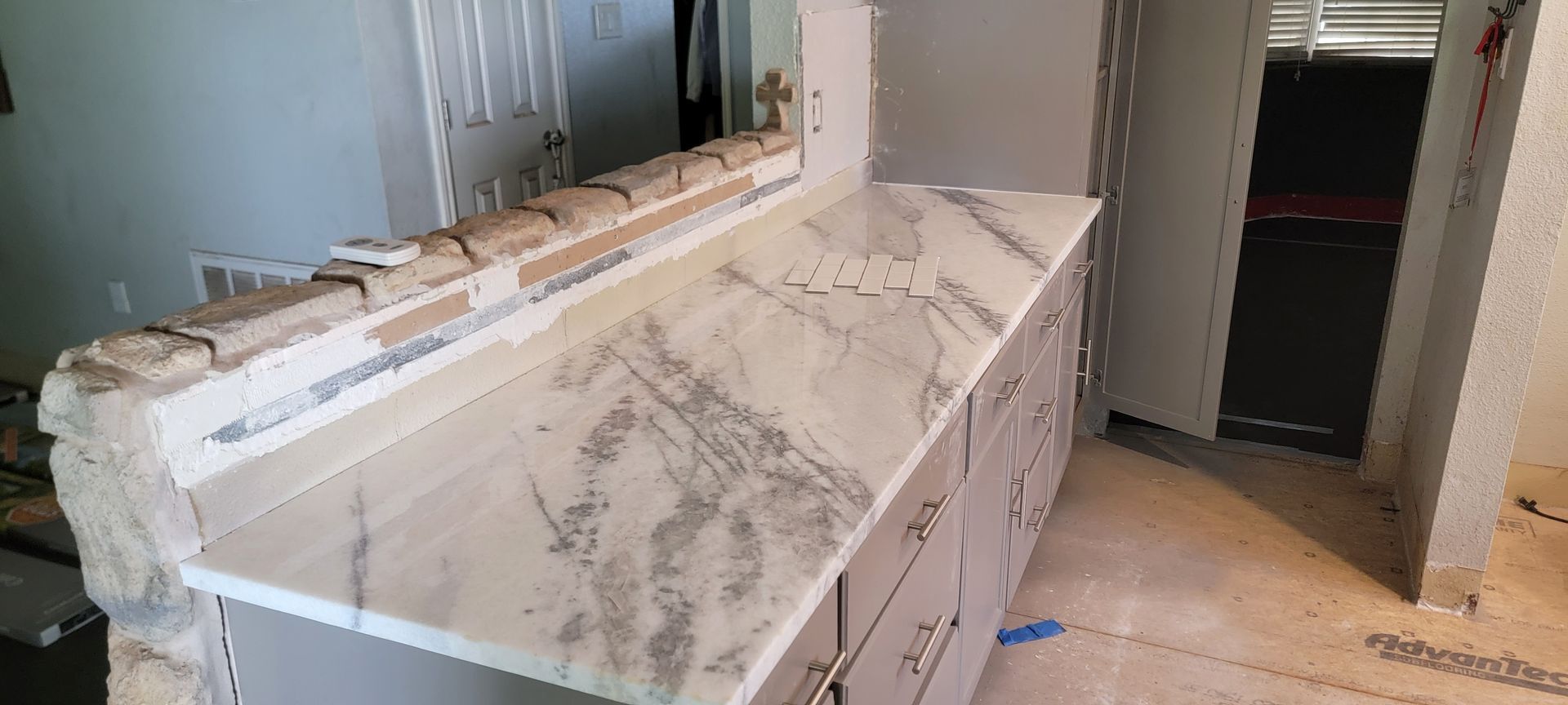 A marble counter top is being installed in a kitchen.