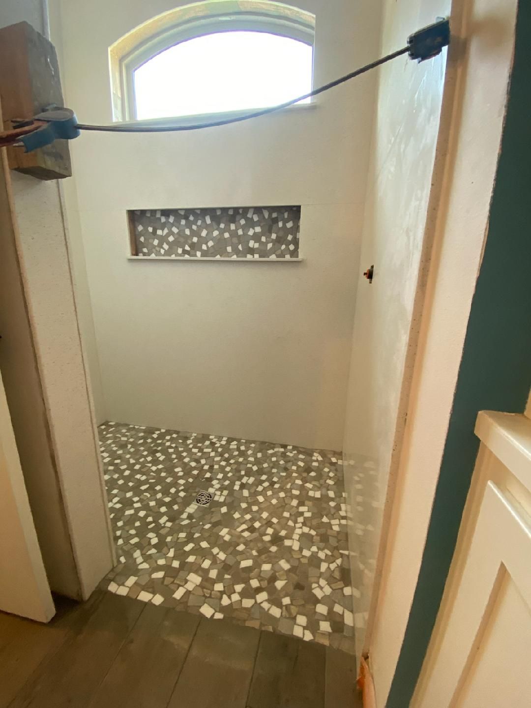 A bathroom with a tiled floor and a window.
