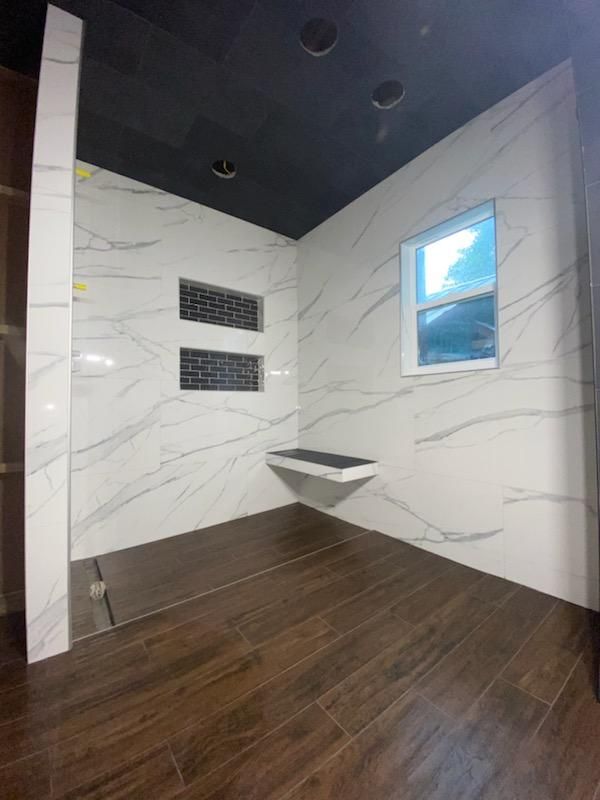 A bathroom with a walk in shower and a window.