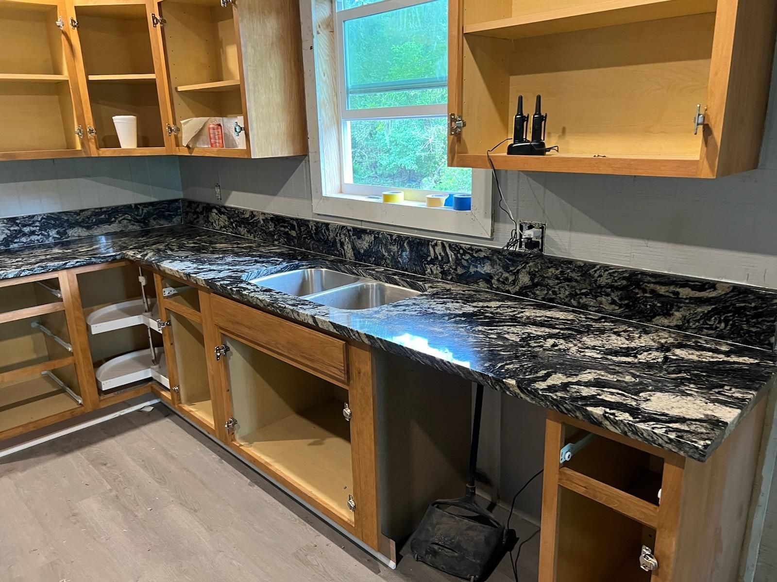 A kitchen with a sink , cabinets , and granite counter tops.