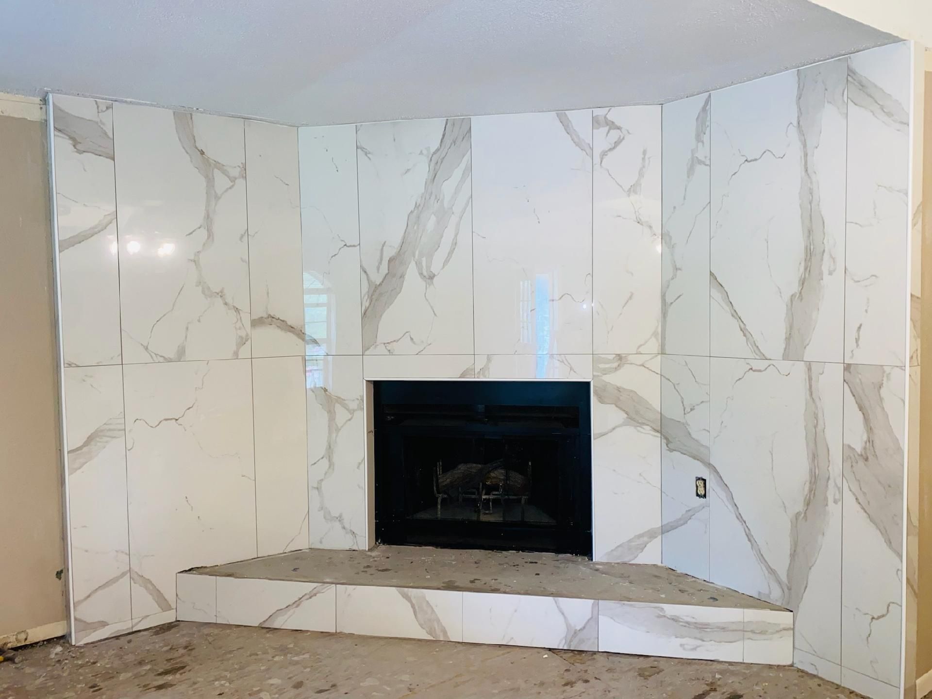 A fireplace is surrounded by marble tiles in a living room.