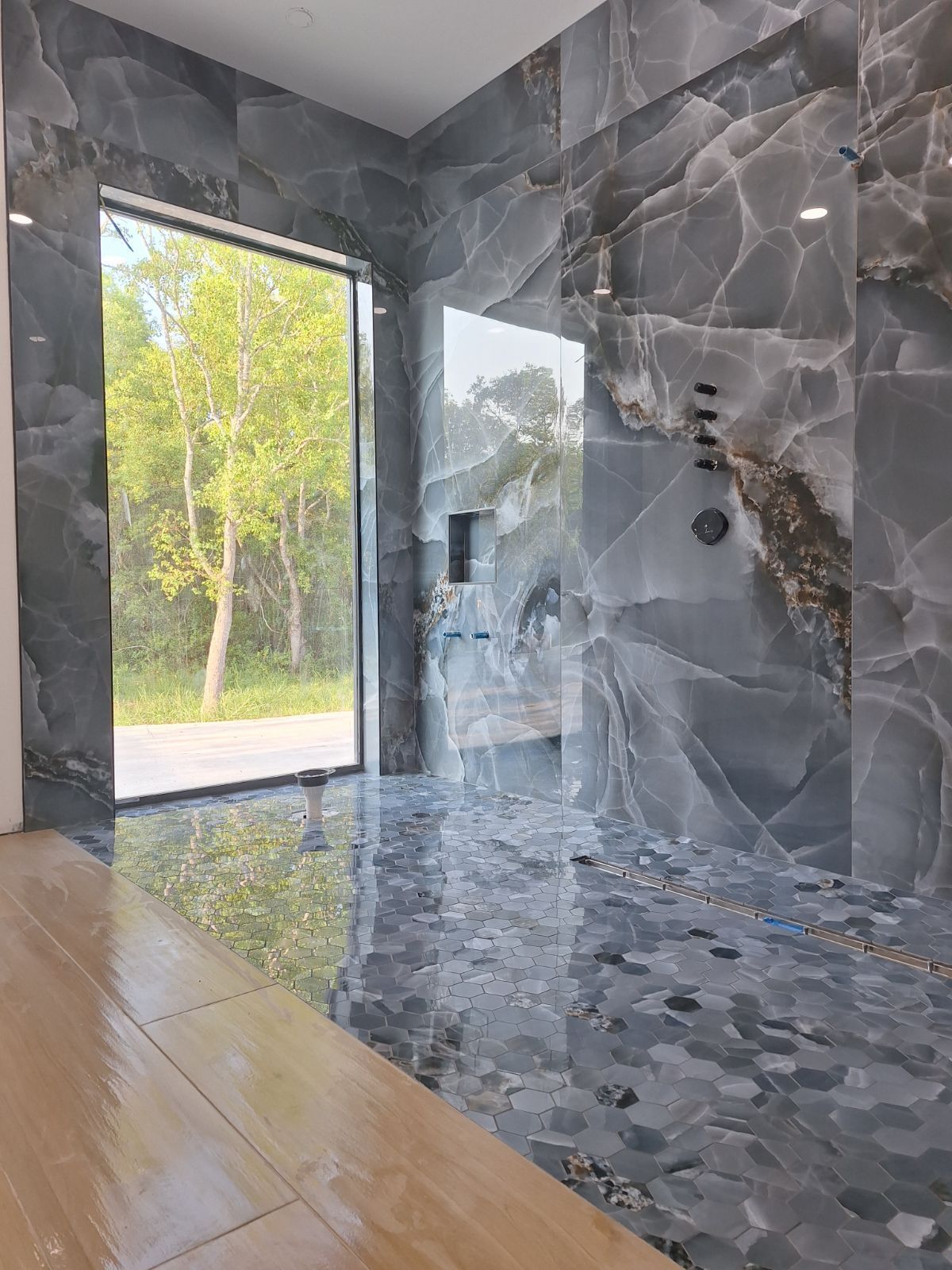 A bathroom with a walk in shower and a large window.