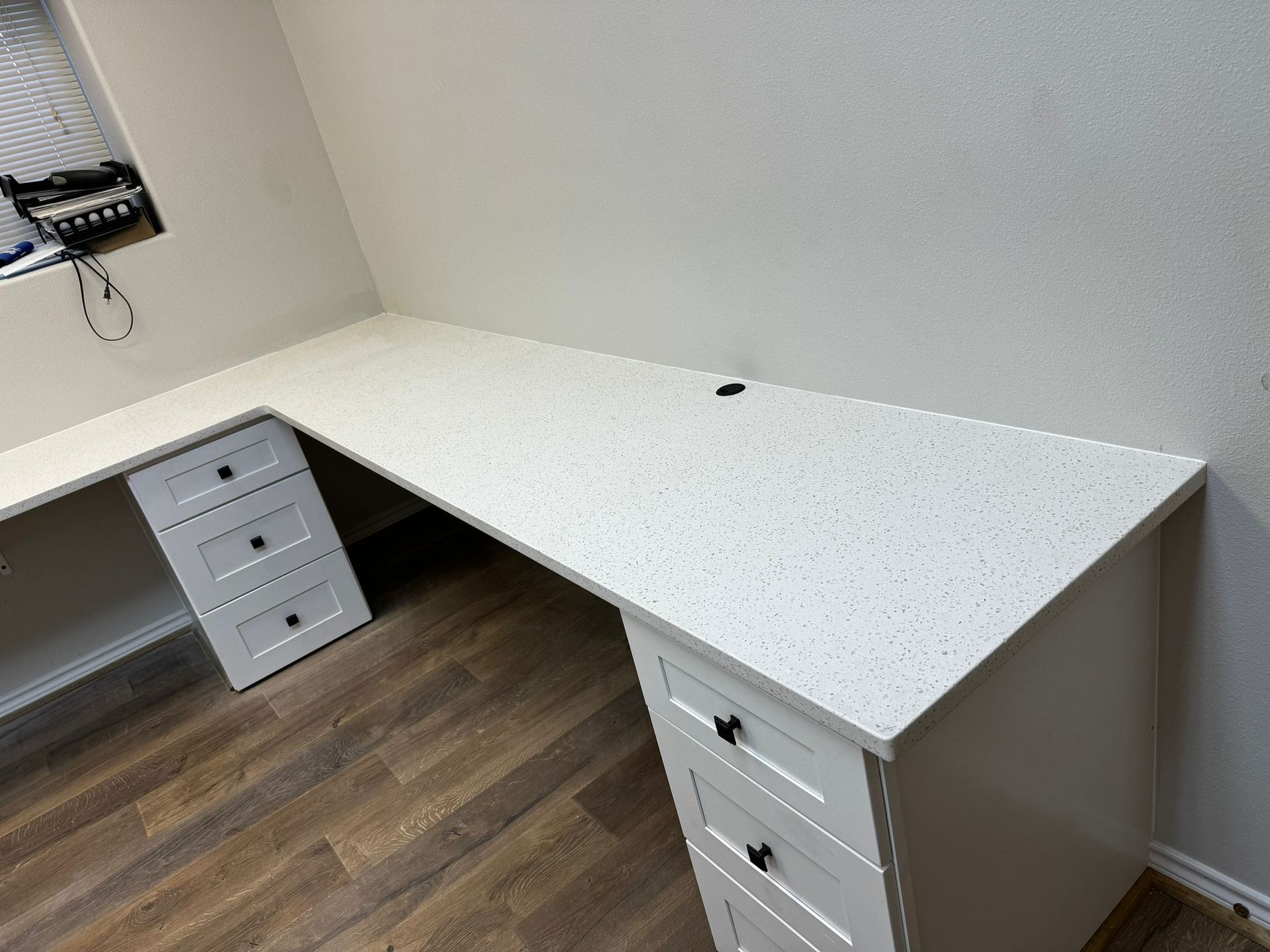 A white desk with a white counter top and drawers in a room.