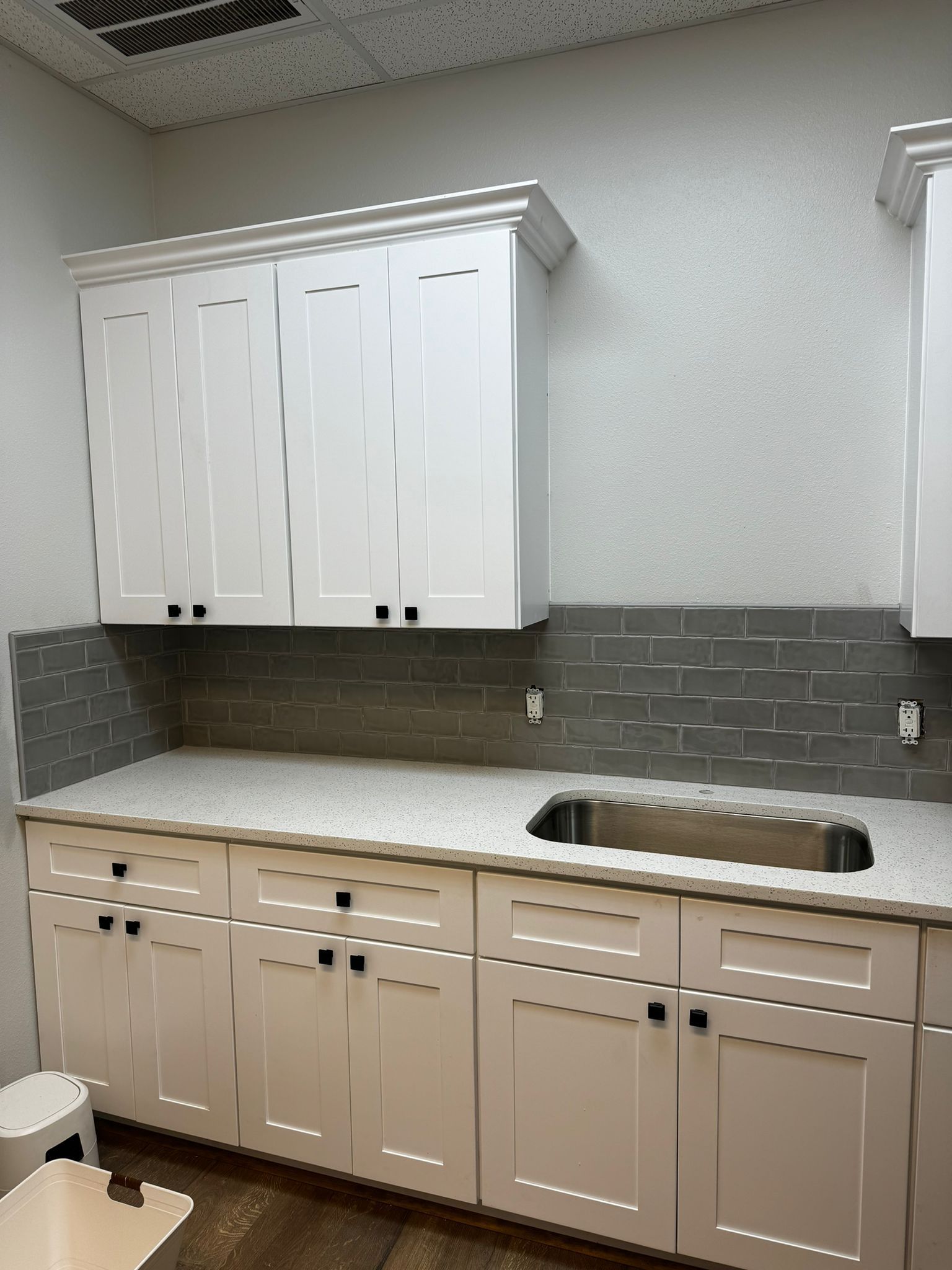 A kitchen with white cabinets and a sink
