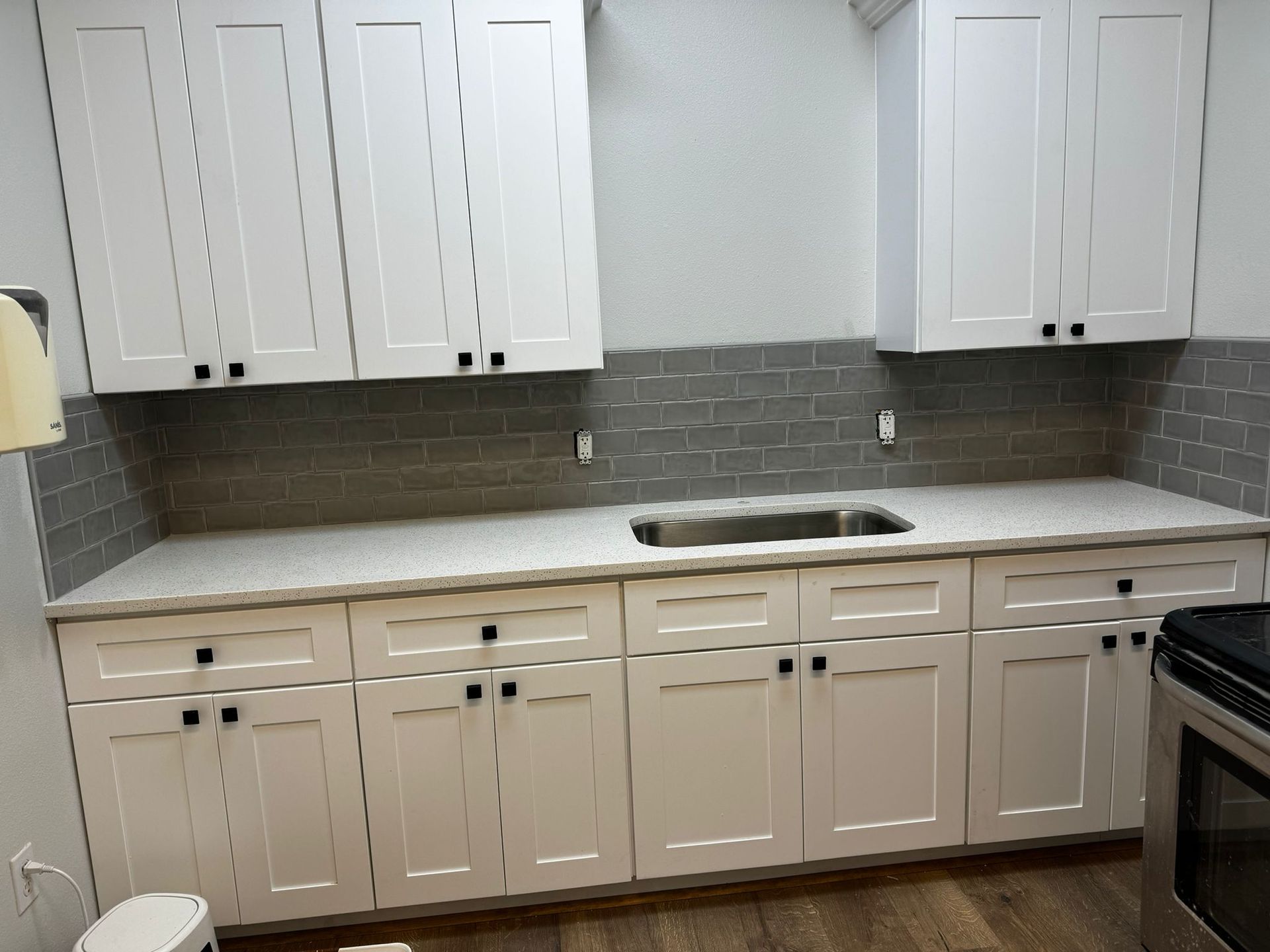 A kitchen with white cabinets , a sink , and a stove.
