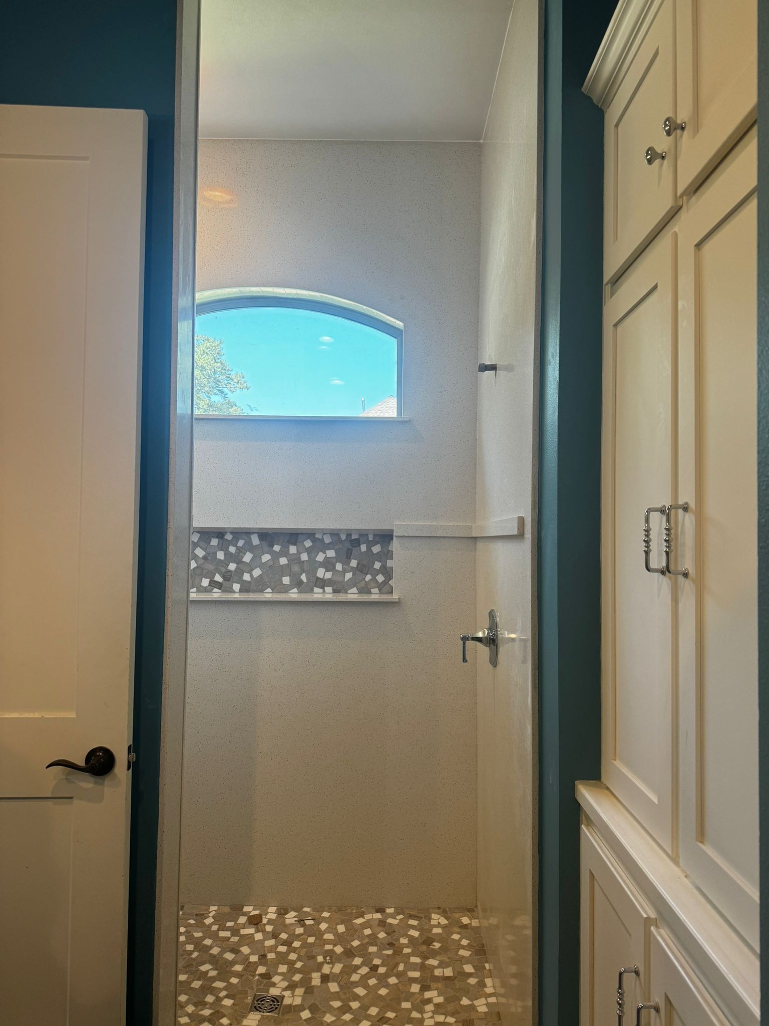A bathroom with a walk in shower and a window