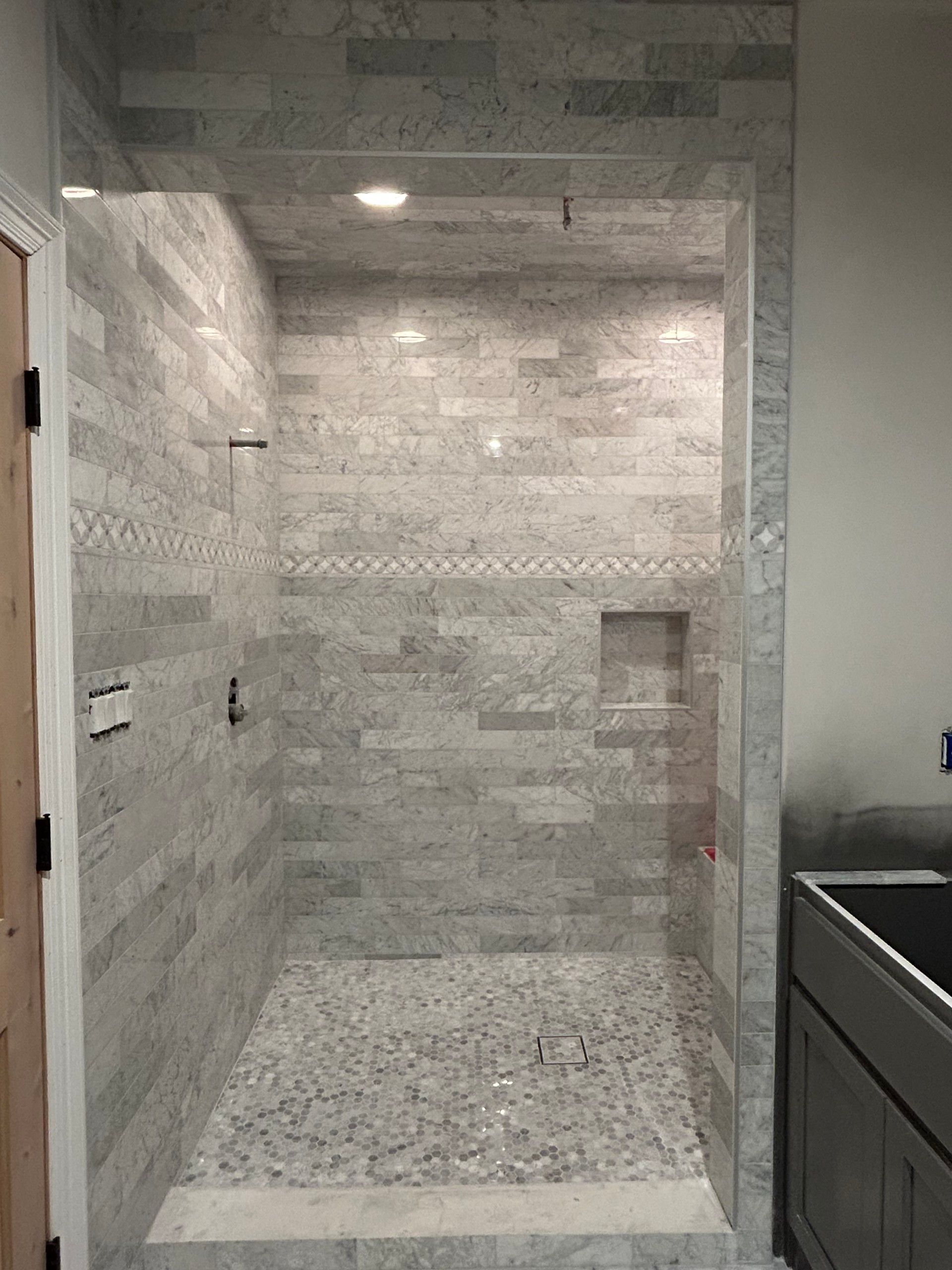 A bathroom with a walk in shower and a sink.