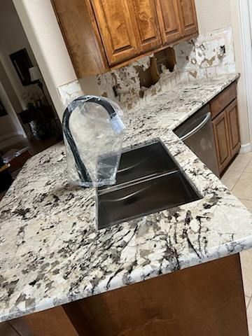 A kitchen with granite counter tops and a stainless steel sink.
