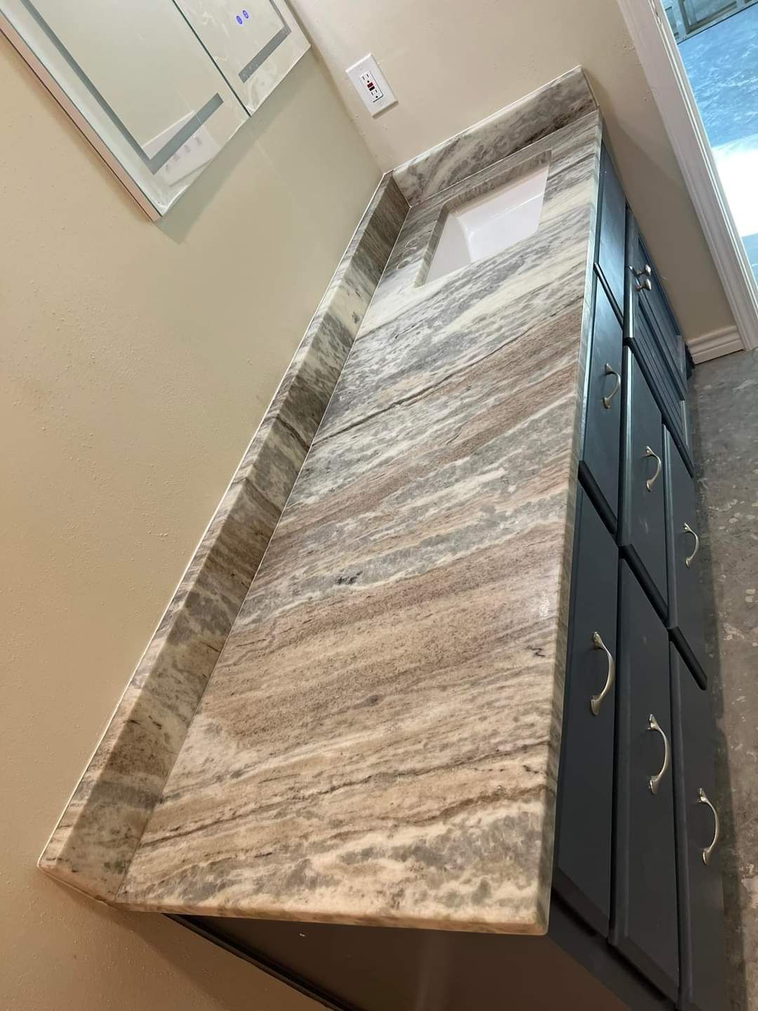 A bathroom vanity with a granite counter top and a sink.