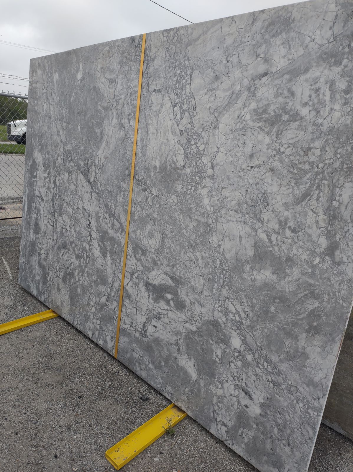 A large gray granite slab is sitting on top of a yellow pallet.