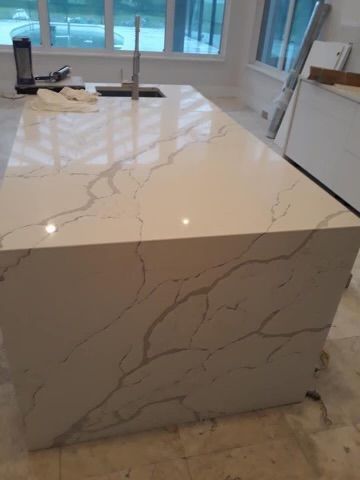 A kitchen with a large white counter top and a sink.
