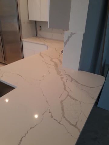 A kitchen with a marble counter top and a sink.