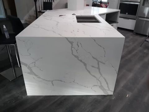 A kitchen with a large white counter top and a sink.