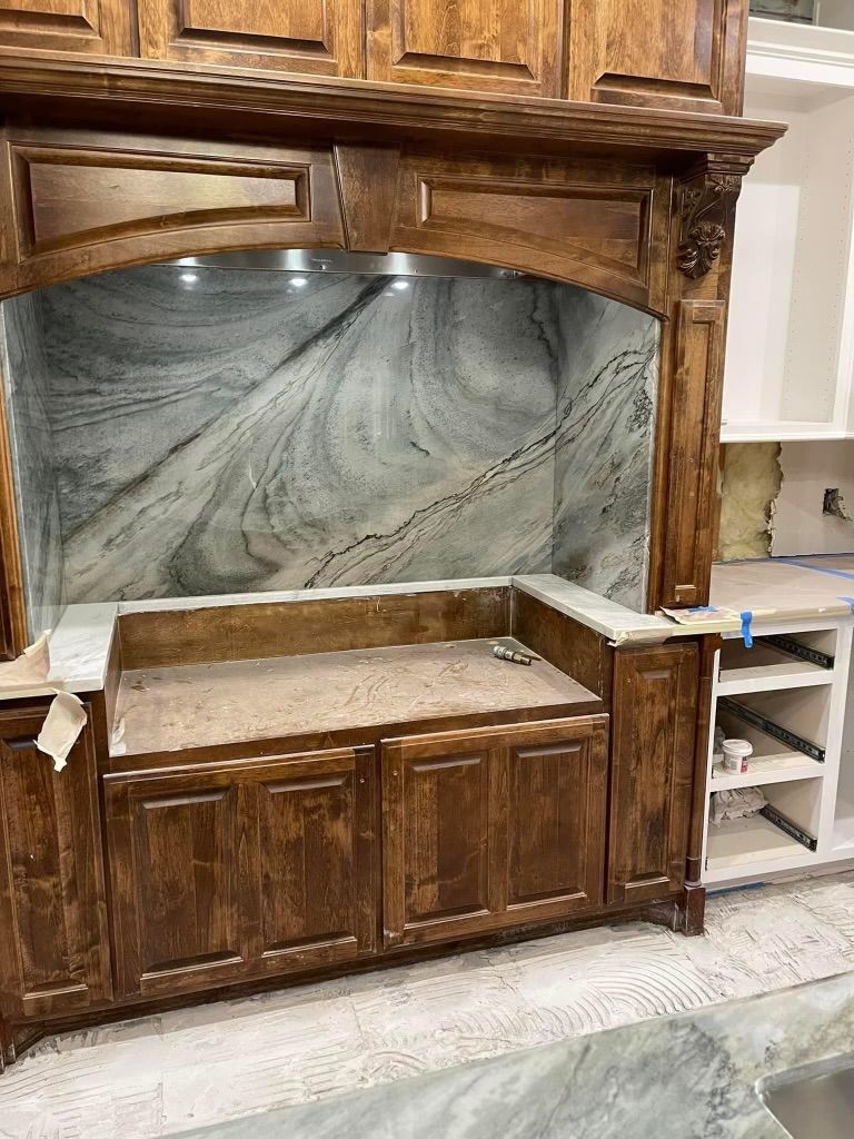 A kitchen with wooden cabinets and a marble counter top.