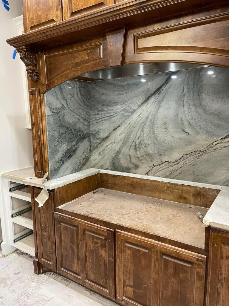 A kitchen with wooden cabinets and marble counter tops.