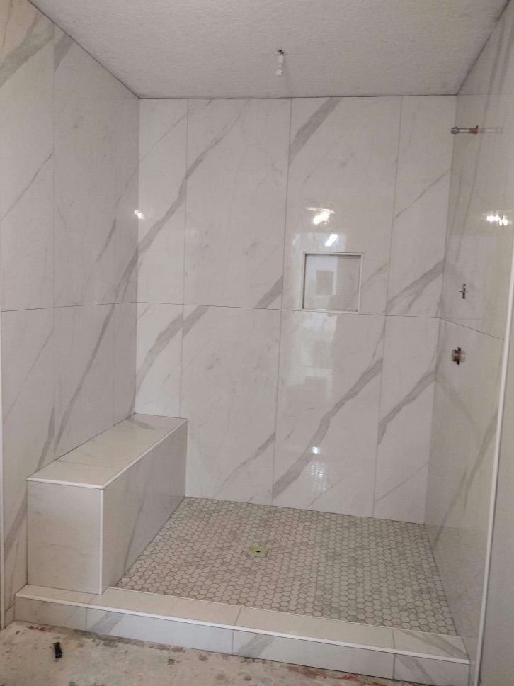 A bathroom with white tiles and a walk in shower.