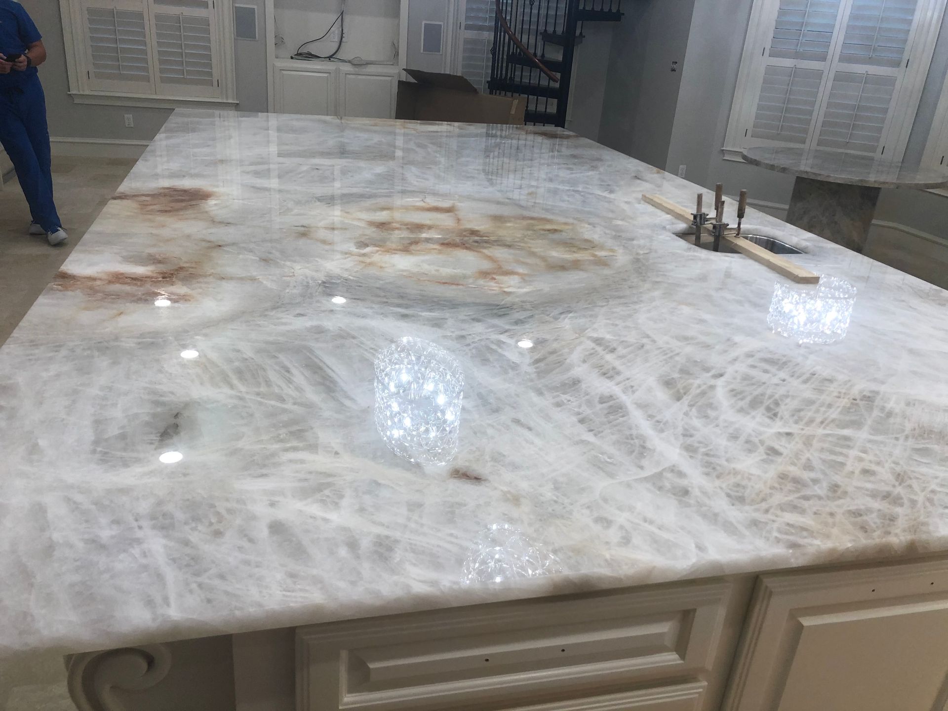 A large white marble counter top in a kitchen with a sink.