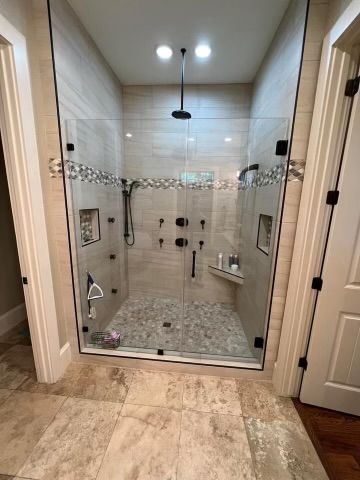 A bathroom with a walk in shower with a glass door.