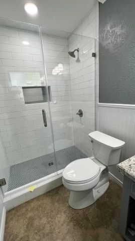 A bathroom with a toilet , shower and sink.