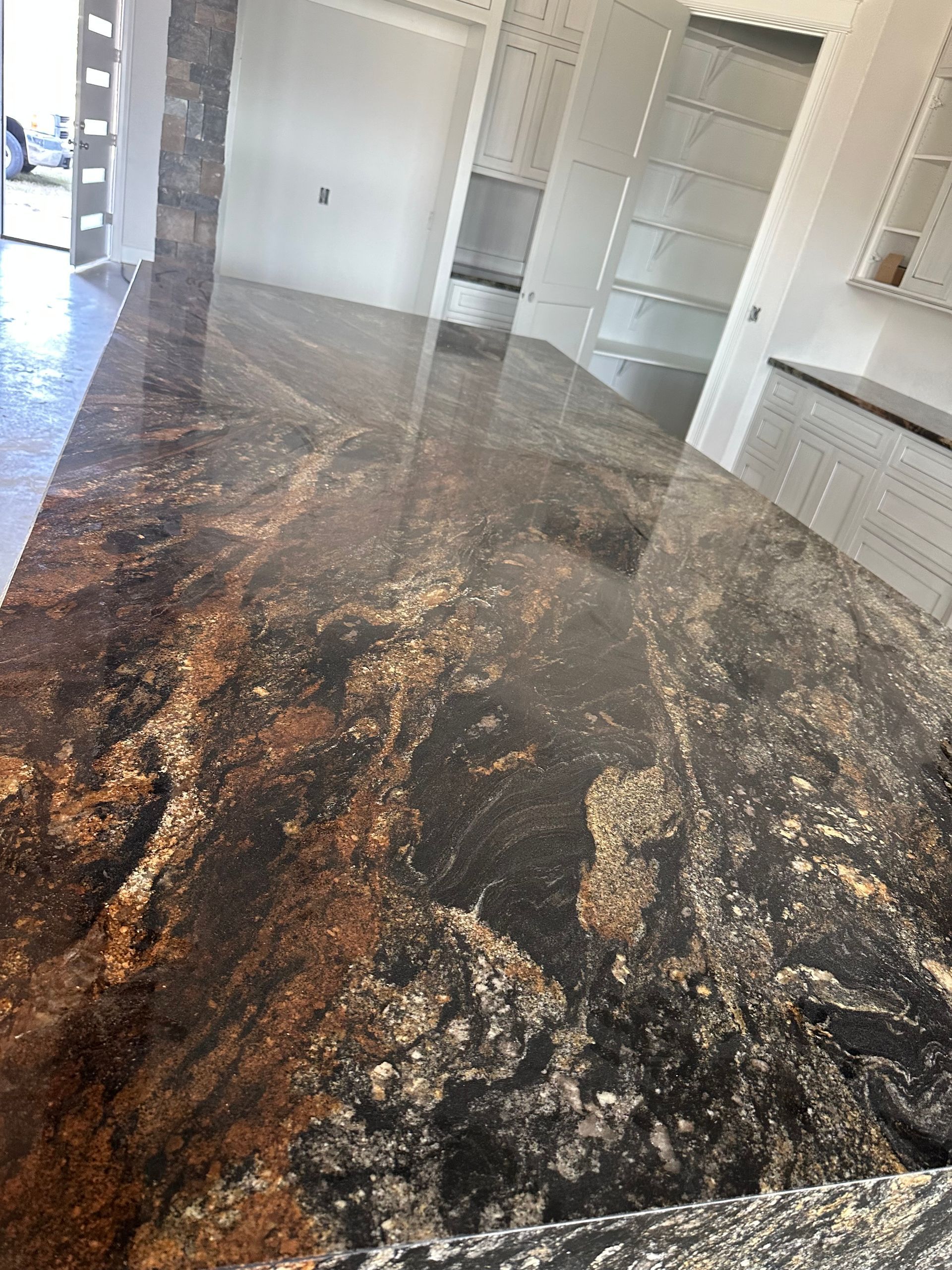 A kitchen with a large granite counter top and white cabinets.
