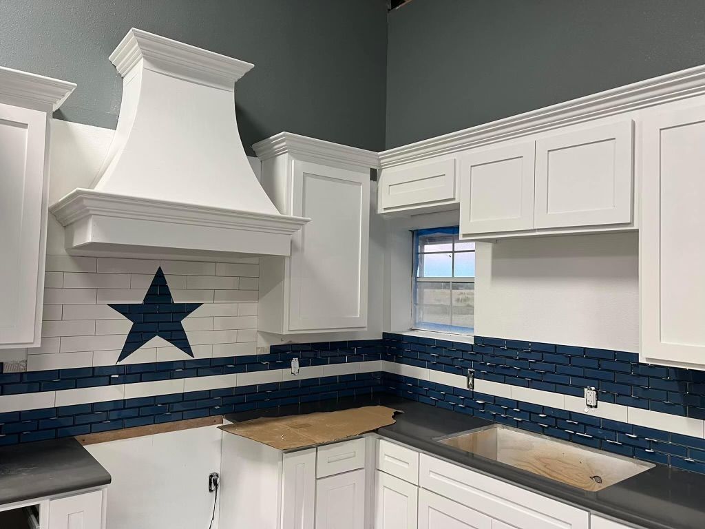 A kitchen with white cabinets and a blue star on the wall.