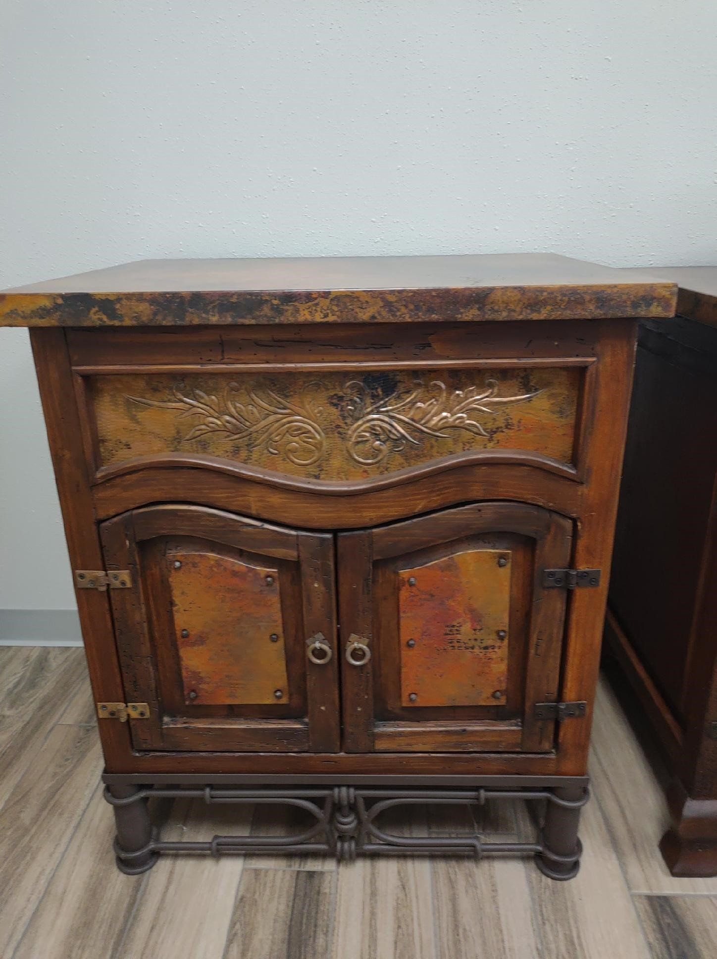 A small wooden cabinet with a copper top is sitting on a wooden floor.