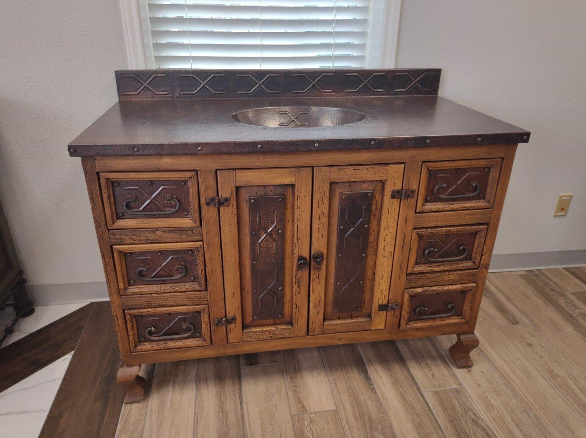 A wooden vanity with drawers and a sink in a room next to a window.