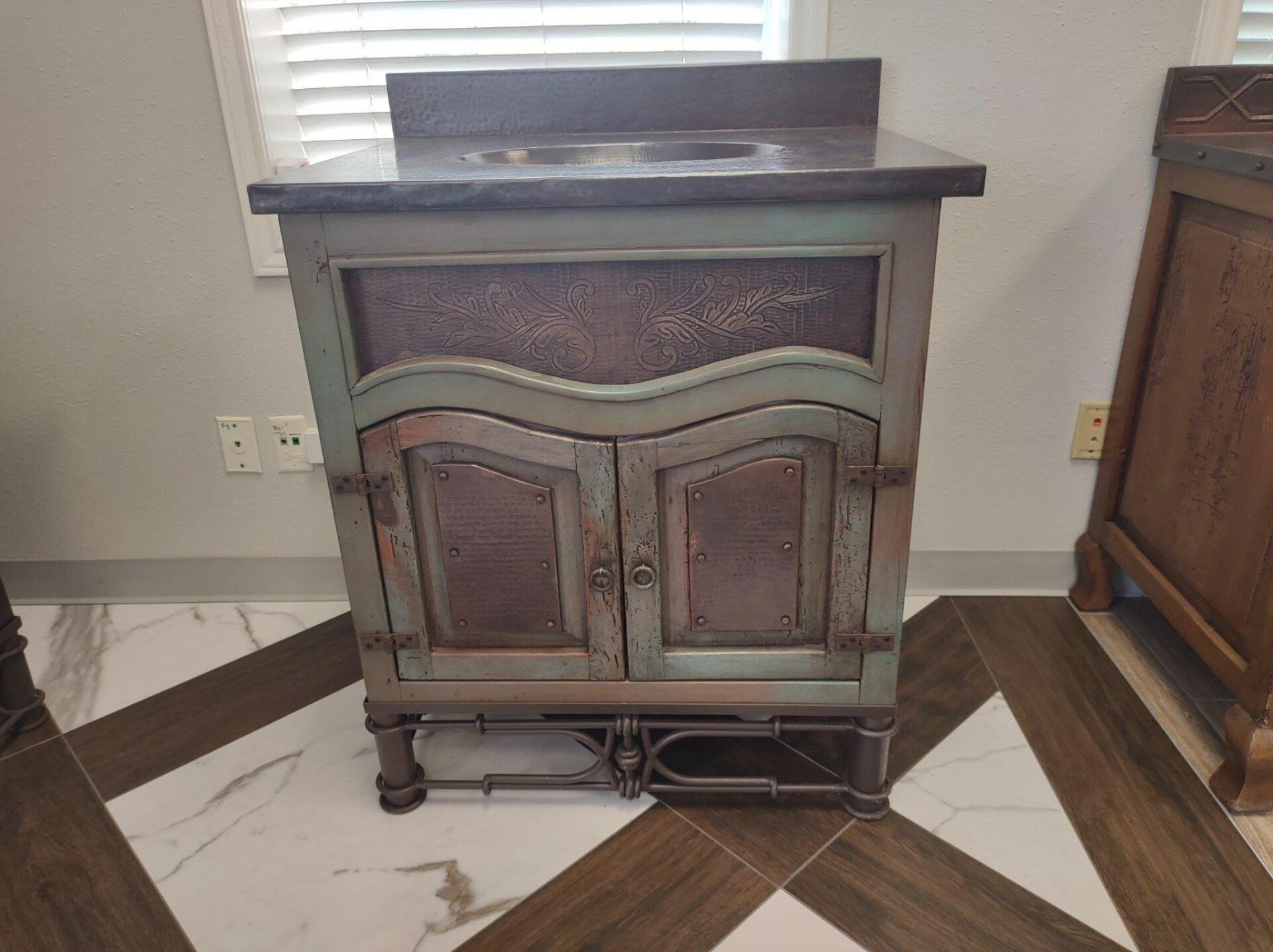 A bathroom vanity is sitting on a tiled floor next to a window.
