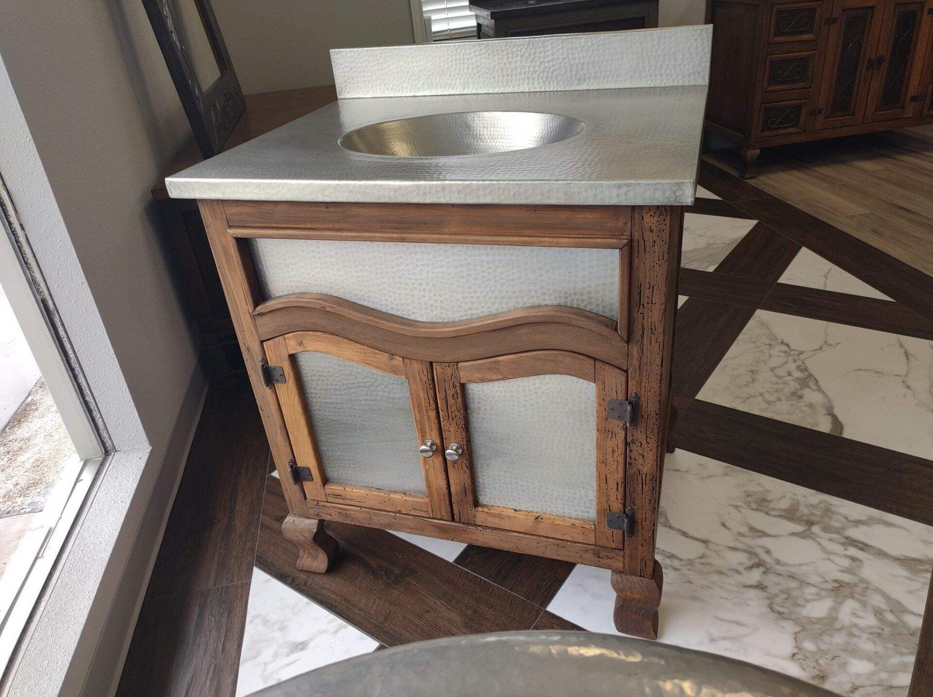 A bathroom vanity with a stainless steel sink on top of it.