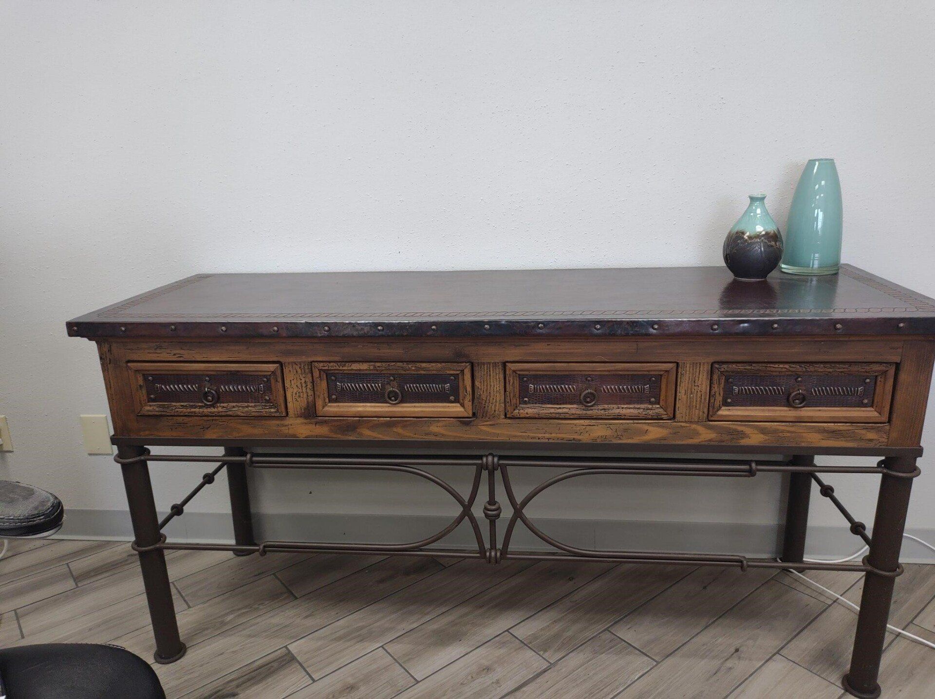 A wooden table with three drawers and two vases on top of it.