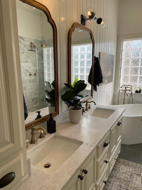 A bathroom with two sinks , two mirrors and a tub.