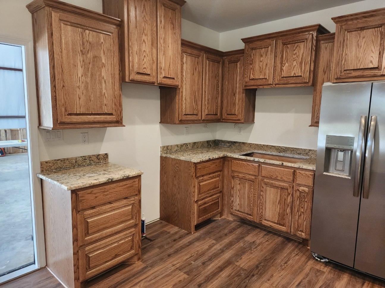 A kitchen with wooden cabinets and a stainless steel refrigerator.