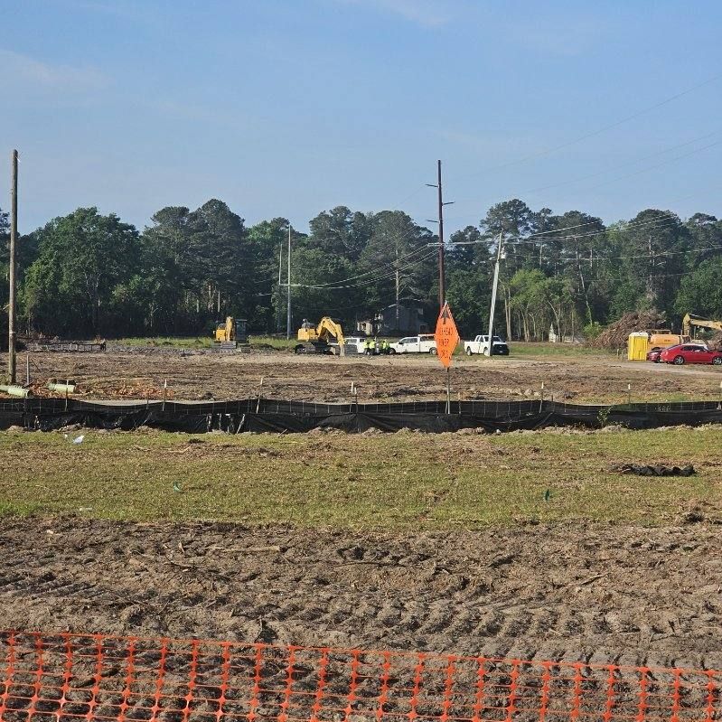 A large dirt field with a fence and trees in the background