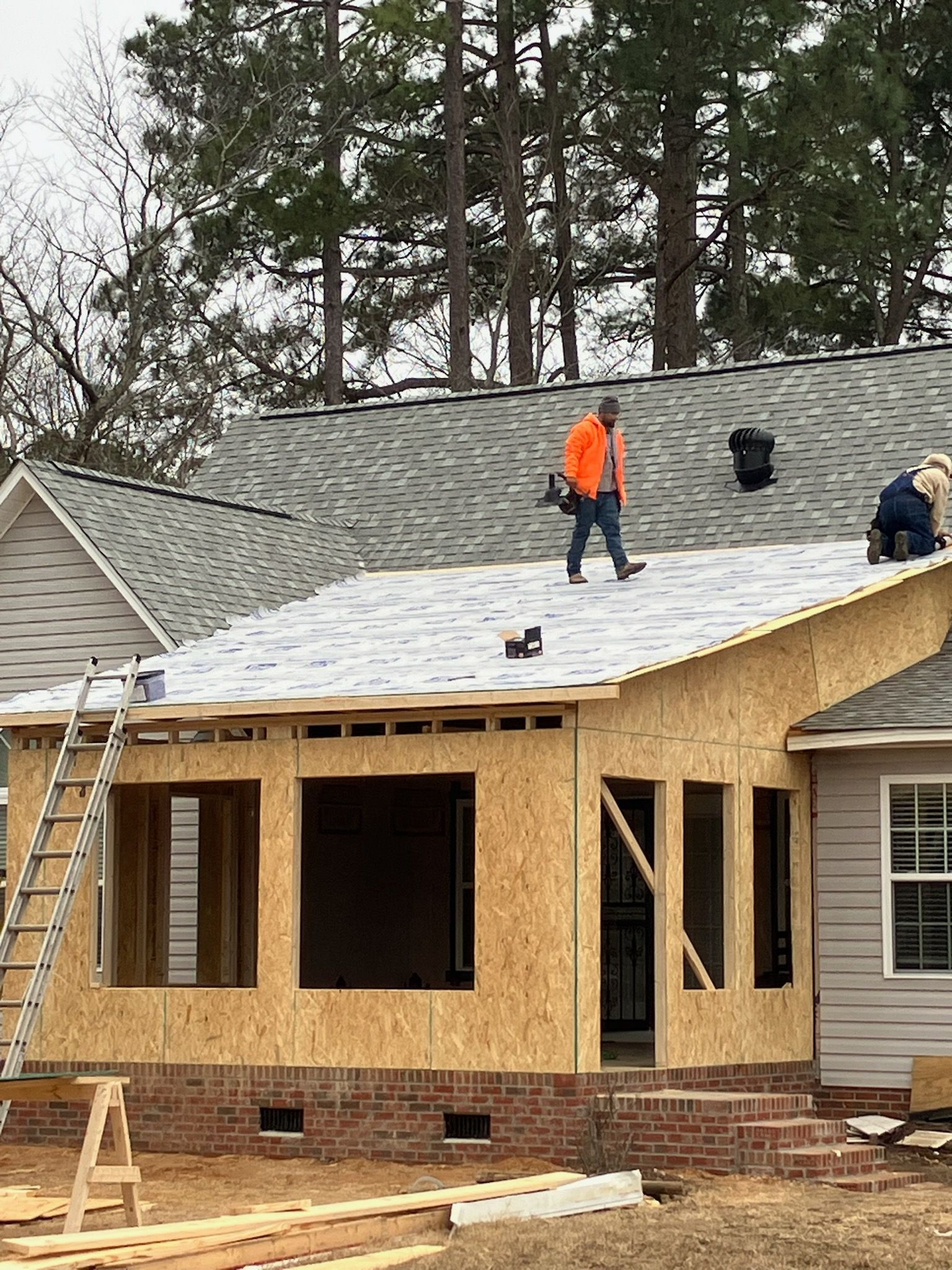 A man is standing on the roof of a house under construction.