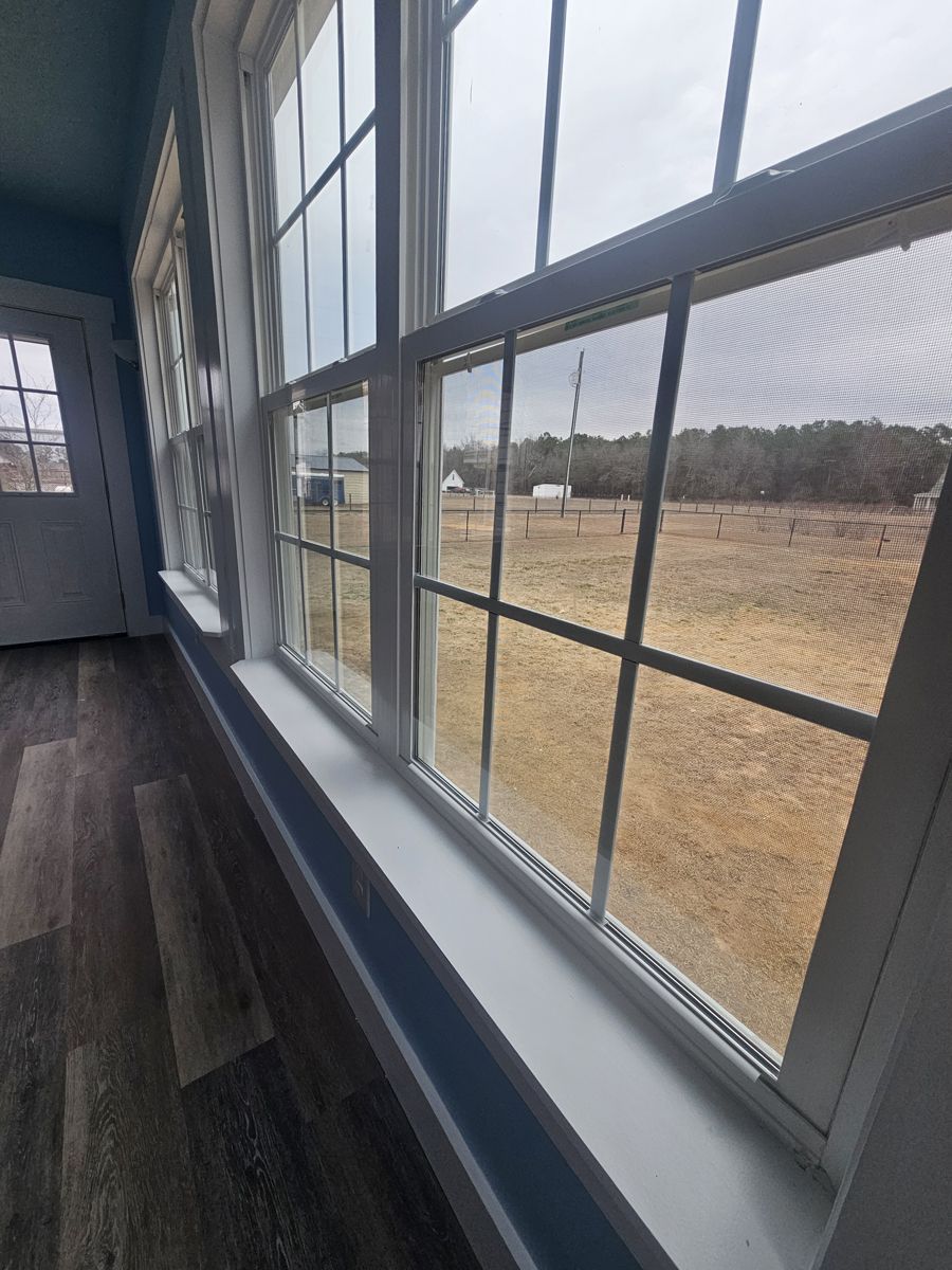 A room with a lot of windows and a view of a field.