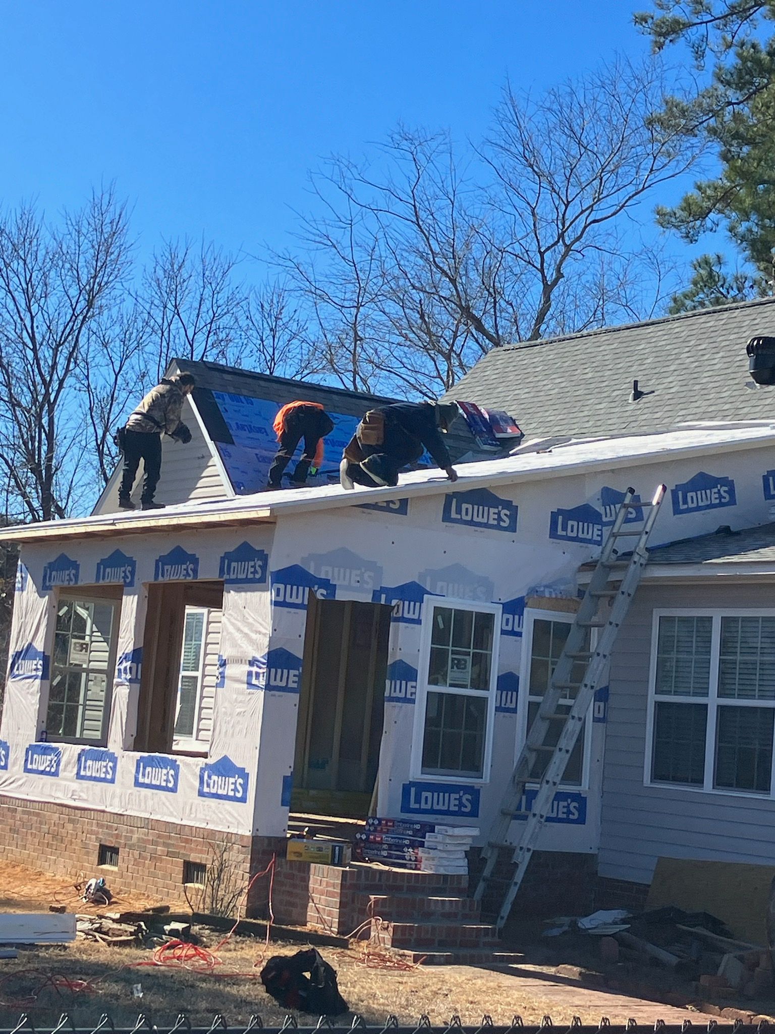 A group of people are working on the roof of a house.