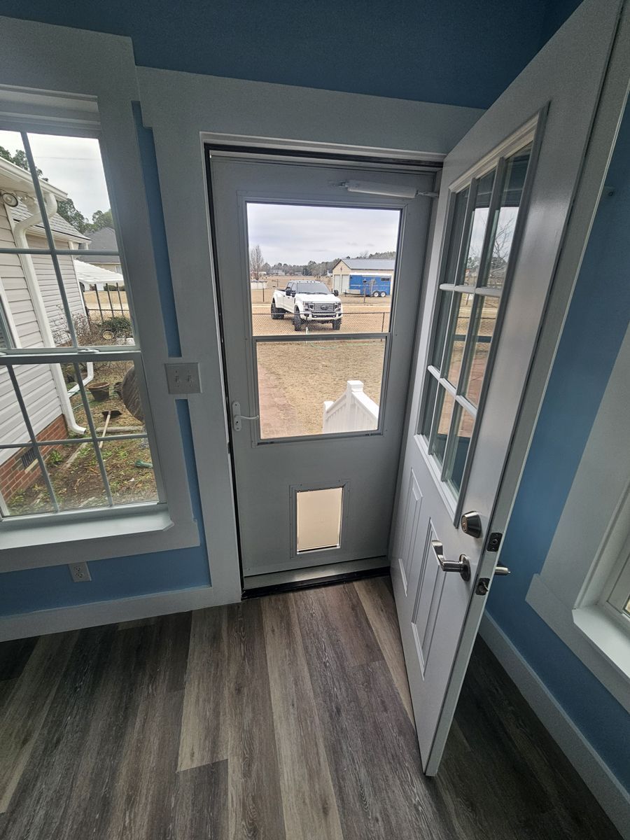 A white door with a window and a dog door in a room.