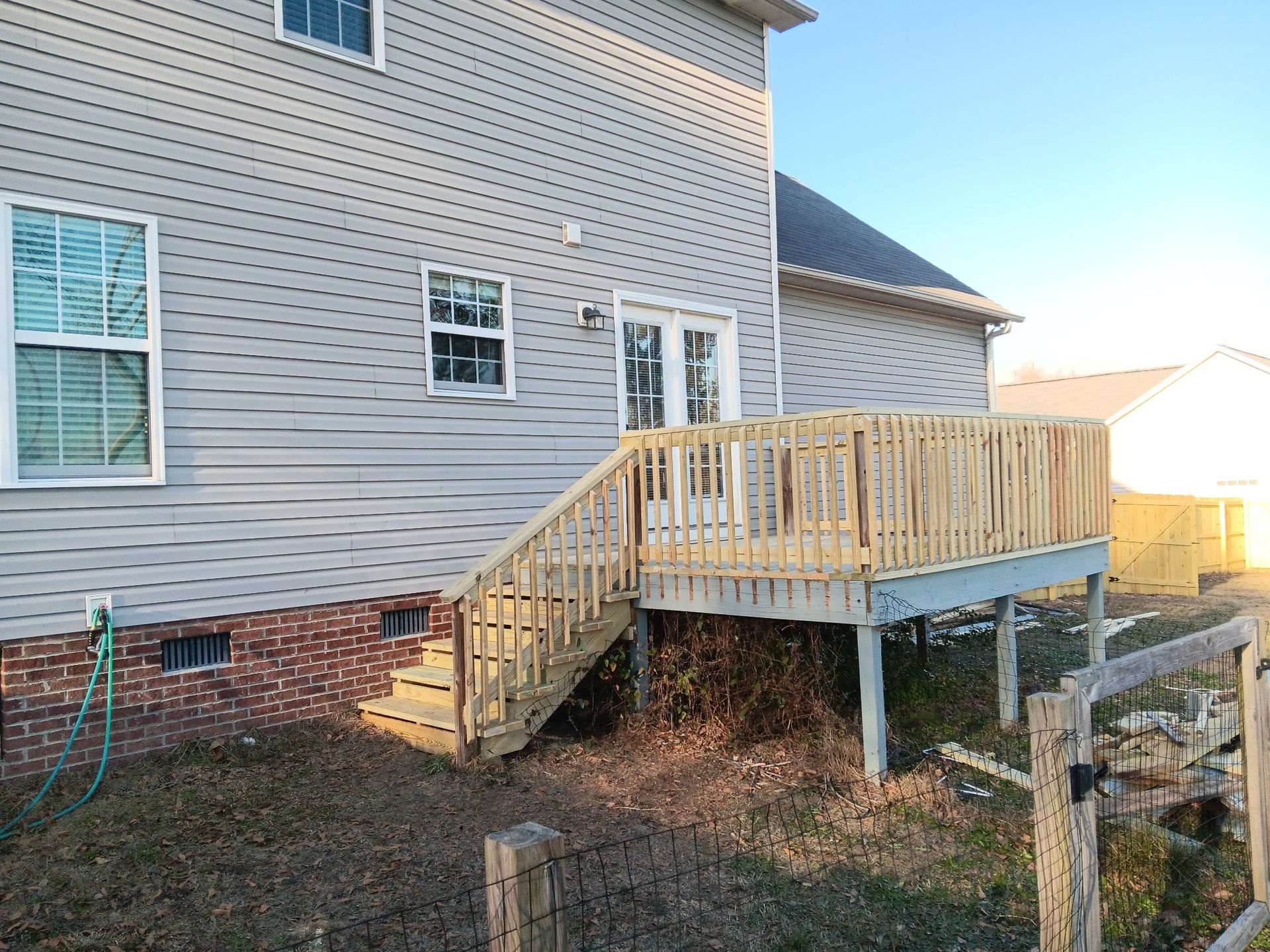 The back of a house with a wooden deck and stairs.