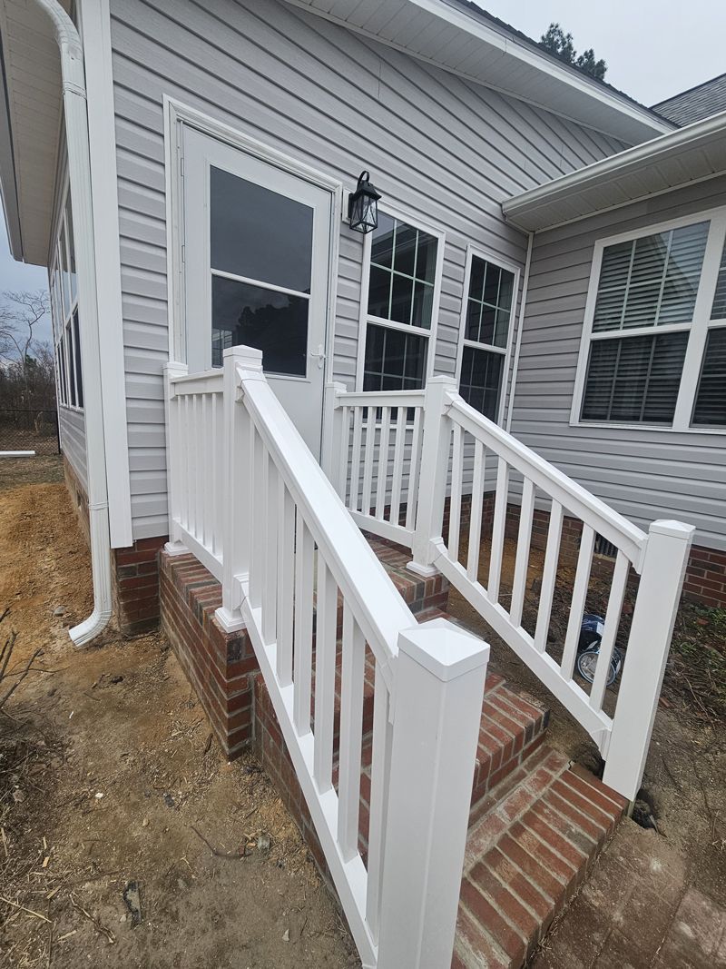 A white railing leads to the front door of a house.